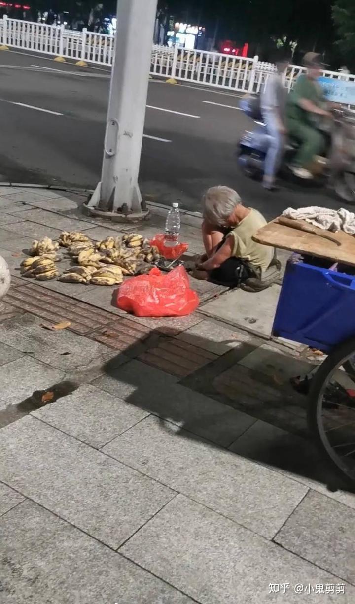 深夜街头蜷缩在香蕉摊旁的老人